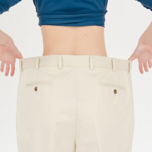 Back view of a person wearing beige pants; waistband is being pulled to show a loose, oversized fit.