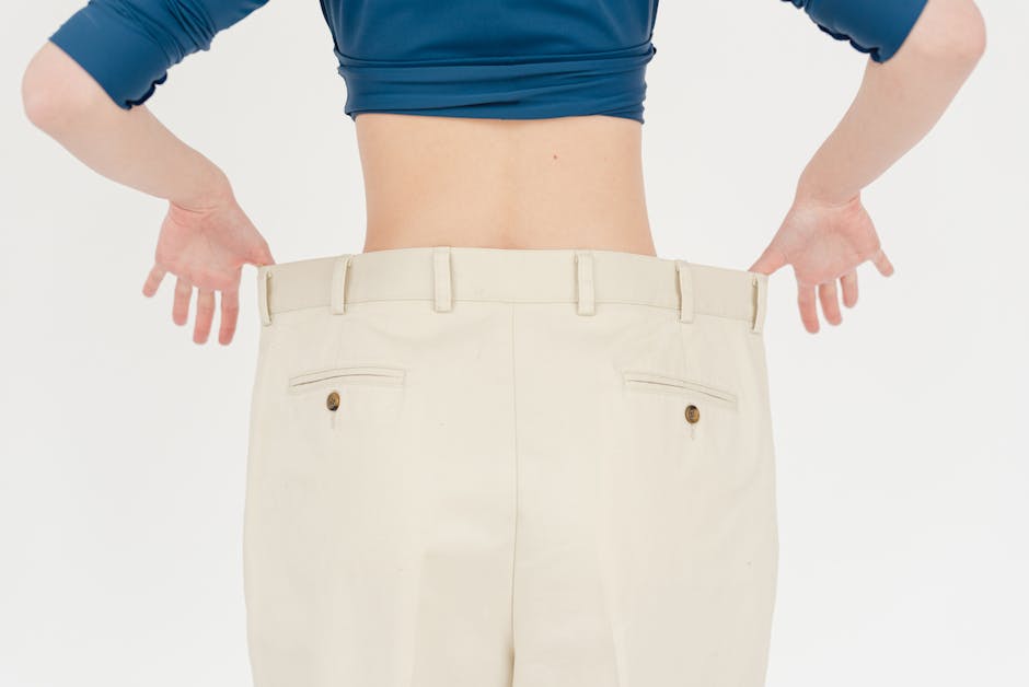 Back view of a person wearing beige pants; waistband is being pulled to show a loose, oversized fit.